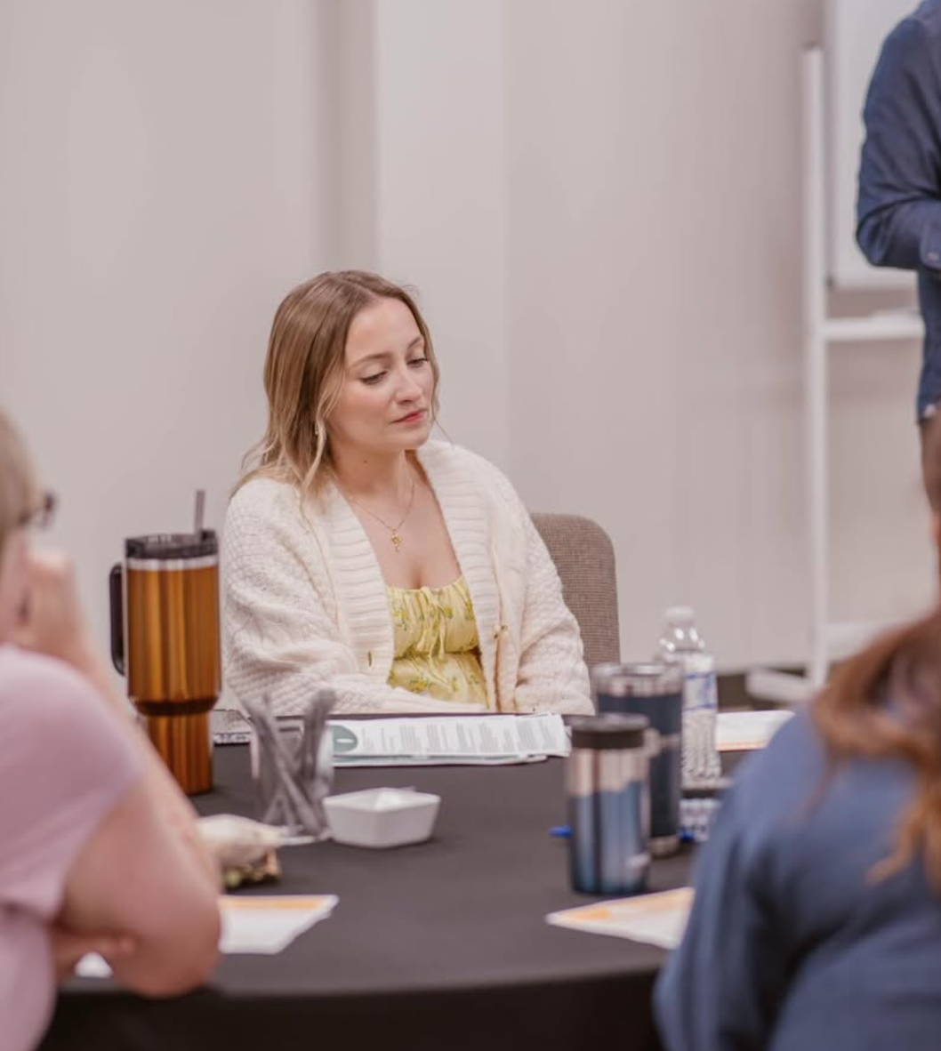 A guest listening at her seat with Next Steps Class materials on the table